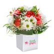 A wave of pure delight flows from this radiant bouquet, elegantly displayed in a crisp white gift bag-the type one might receive for a joyful occasion from a trusted Becontree Heath florist. Abundant carnations in warm coral, peach, and striking red burst from the core, their ruffled petals filled with vibrancy and softness. Cheerful white daisies with golden-lime centres punctuate the arrangement, filling it with a brightness reminiscent of sunny afternoons spent in Mayesbrook Park. Ethereal sprays of baby's breath drift throughout, each tiny blossom lending an airy grace to the bouquet. Hidden among the open blooms, several unopened purple-tinged buds add subtle intrigue. Deep, shiny green foliage wraps the base, giving the entire bouquet a lush, rounded finish. The arrangement is bathed in fresh, even light, standing out against a pure white backdrop to highlight every nuance-whether the tender gradient of a carnation petal or the shimmer of a leaf. With its sturdy white ribbon handles, the gift bag is both elegant and practical, ready for delivery to any doorstep across Becontree Heath. Designed to brighten birthdays, anniversaries, or simply show heartfelt appreciation, this bouquet radiates the thoughtful care and spirit of a local florist, offering a touch of celebration to any day.